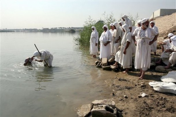 A Mandaean Sabian priest baptizes a believer on the banks of the Tigris river in Baghdad, Iraq, Monday, Nov. 5, 2007. Mandaeanism is a monotheistic religion whose followers regard John the Baptist as their prophet. The Iraq conflict reduced the number of Mandaeans living in the country to approximately five thousand, as most of them fled to neighboring countries under threat of violence. (AP Photo/Hadi Mizban)